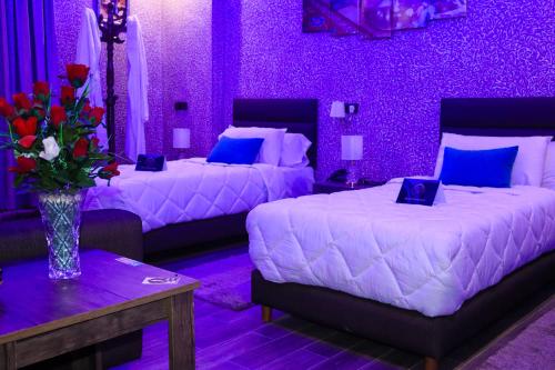 a purple bedroom with two beds and a vase of flowers at Hotel Cafe Sahariano in Smara