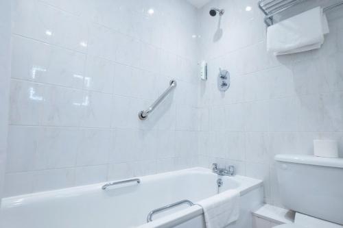 a white bathroom with a tub and a toilet at The Hickstead Hotel By Uno-FREE PARKING in Bolney