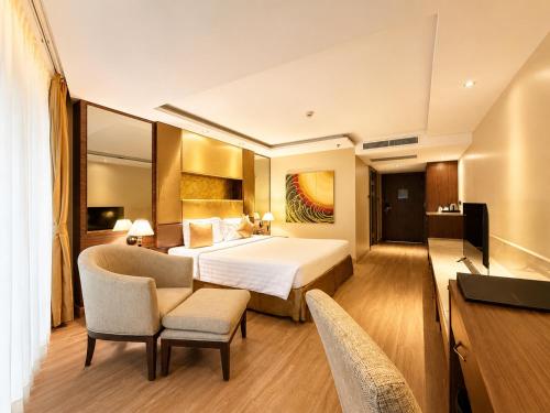 ein Hotelzimmer mit Bett, Schreibtisch und Stühlen in der Unterkunft Nova Gold Hotel Pattaya in Pattaya