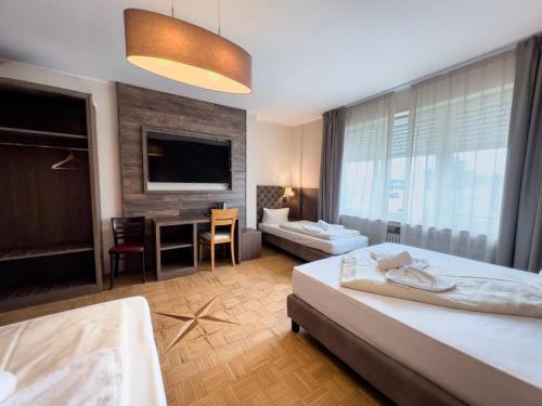 a bedroom with two beds and a desk and a television at Hotel Il Cavallino in Warendorf