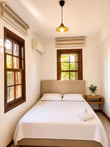 a bedroom with a large white bed with two windows at White City Pension in Antalya
