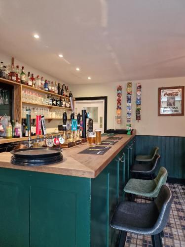 a bar with green cabinets and two bar stools at Red Lion Inn in Milfield