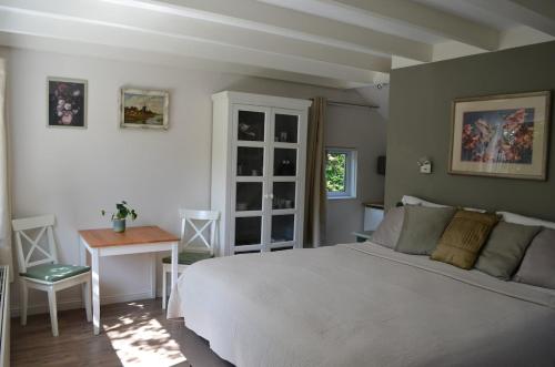 a bedroom with a bed and a table and a desk at Cozy Cottage in Schoorl