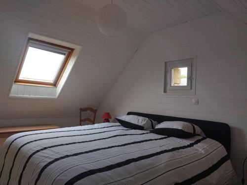a bedroom with a bed with two pillows and a window at Penty vue sur mer in Tréguennec