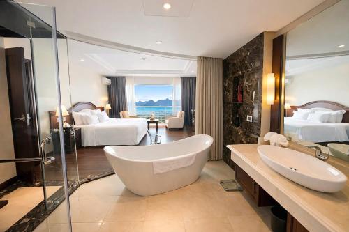 a bathroom with a bath tub and a bedroom with two beds at Sai Gon Ha Long Hotel in Ha Long