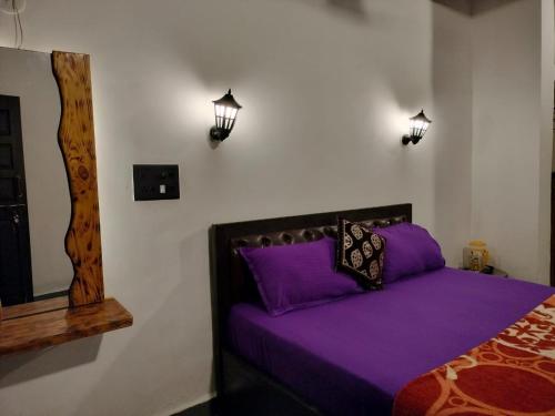 a bedroom with a bed with purple sheets and lights at guest house carolina in Colva