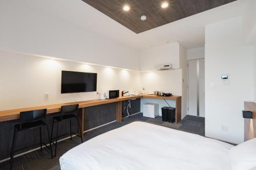 a hotel room with a bed and a desk with a television at HIT Tenjin in Fukuoka