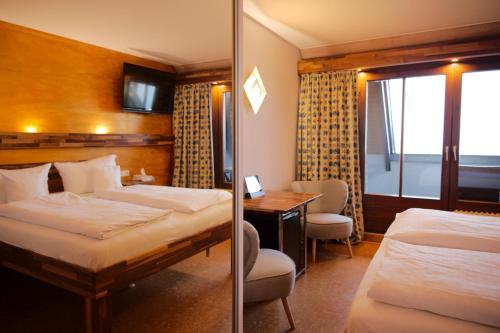 a hotel room with two beds and a desk at BoutiqueHotel KAPUZINERGARTEN in Breisach am Rhein