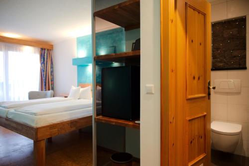 a bedroom with a bed and a room with a tv at BoutiqueHotel KAPUZINERGARTEN in Breisach am Rhein