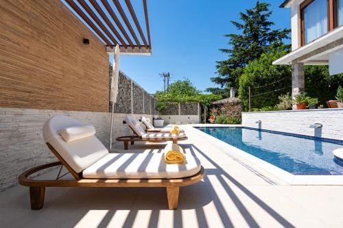 a patio with two lounge chairs and a swimming pool at Villa D Apartments in Podlastva