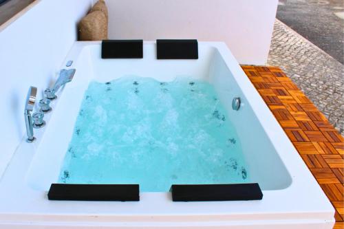 a bath tub filled with blue water sitting on a table at Villa Penim - Countryside Villa with Jacuzzi, Garden with BBQ & Stunning Views in Sesimbra