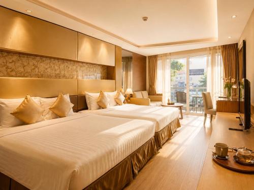 ein Hotelzimmer mit einem großen Bett und einem Fernseher in der Unterkunft Nova Gold Hotel Pattaya in Pattaya