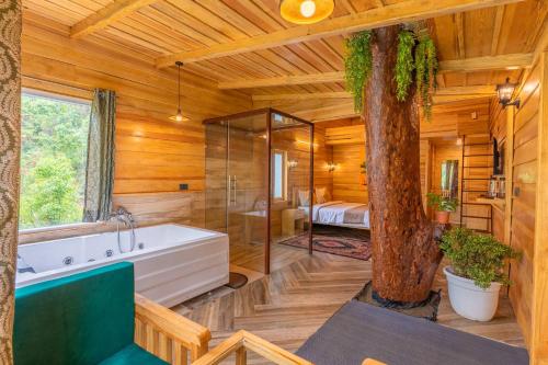 a bathroom with a tub and a tree in it at Echor Malusara Lakeview Retreat Bhimtal in Bhīm Tāl