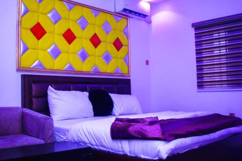 a bedroom with a bed and a painting on the wall at G Point Hotel Ikeja in Mama