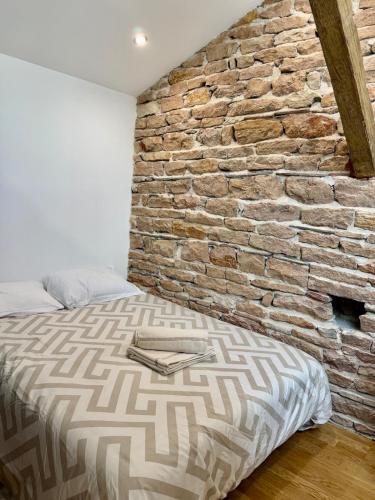 a bedroom with a brick wall next to a bed at Douceur Suite - 2 bedrooms in Mâcon