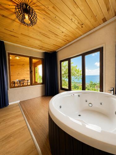 eine große Badewanne in einem Zimmer mit Fenstern in der Unterkunft Bungaport Luxury Bungalows&Suits in Rize