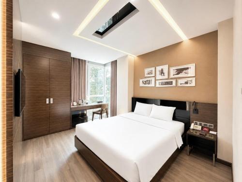 a bedroom with a large white bed and a desk at Queen Ann Hotel in Ho Chi Minh City