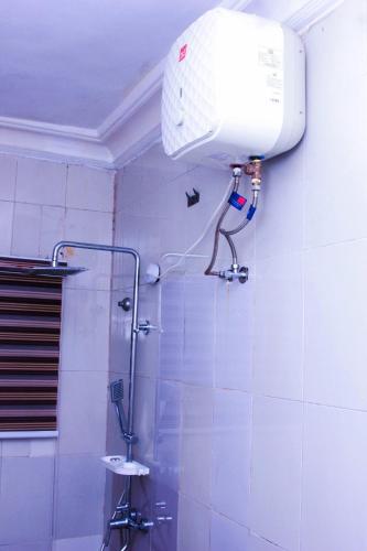 a bathroom with a shower with a blow dryer on the wall at G Point Hotel Ikeja in Mama
