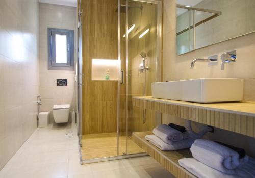 a bathroom with a sink and a shower with towels at MarGio Olive House in Galissas