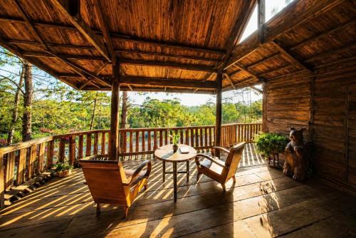 a wooden porch with a table and chairs on it at Sóc House Măng Đen in Kon Plong