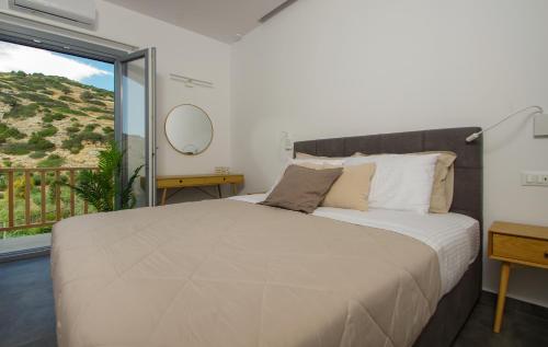a bedroom with a large bed and a large window at MarGio Olive House in Galissas