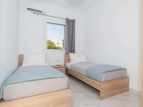 two beds in a room with a window at Dreamy Charaki 2 Bd Villa with Private Pool in Haraki