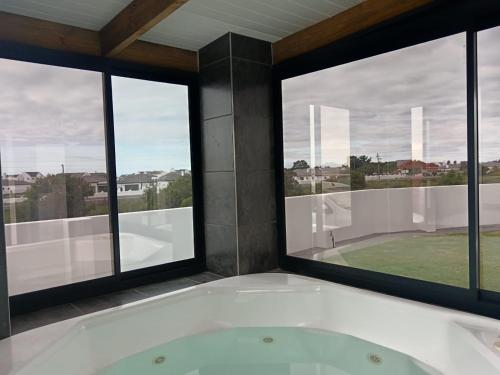 a bath tub in a room with windows at Kwagga Inn in Stompneusbaai