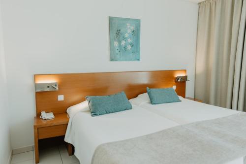 a bedroom with a large white bed with blue pillows at Hotel Sao Sebastiao de Boliqueime in Boliqueime