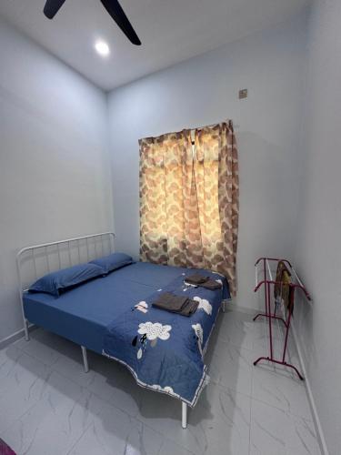 a bedroom with a bed with a blue comforter and a window at HomestayDino in Kuala Terengganu