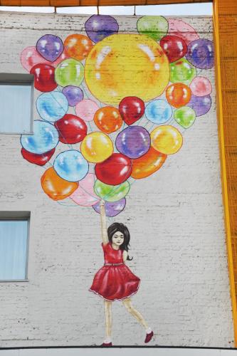 a painting of a woman holding a bunch of balloons at City Hotel Shymkent in Shymkent