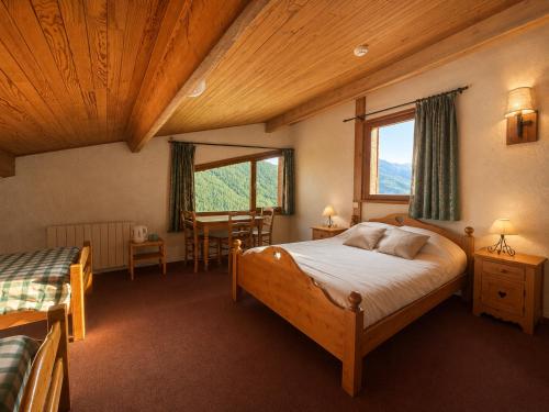 a bedroom with a bed and a window and a table at La Lobio in Molines-en-Queyras