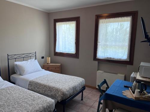 a bedroom with two beds and a desk and two windows at Agriturismo Papaveri & Papere in Caltana