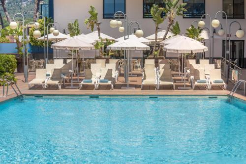 a swimming pool with lounge chairs and umbrellas at htop Jadhe SPA 4Sup - Bliss in Calella