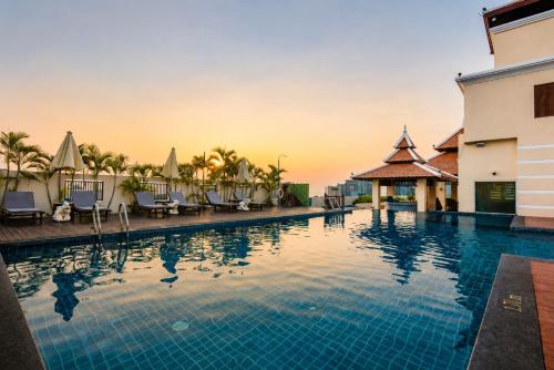 a pool at a resort with chairs and a sunset at Aiyara Palace in North Pattaya
