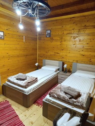 two beds in a room with wooden walls at Kuća za odmor Jarić in Ležimir