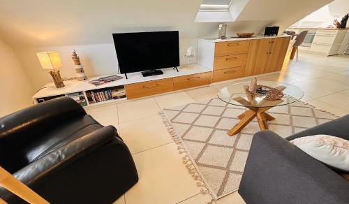 a living room with a couch and a television at Fewo Grachtenhimmel- Appartement zum Entspannen in Krummhörn