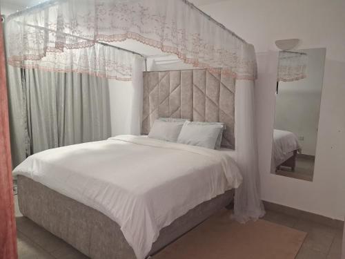 a bedroom with a white bed with a canopy at PAZURI - Homes2 in Voi