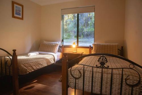 a bedroom with two beds and a window at #2 Walpole Wilderness Resort chalet. Spa + forest. in Walpole