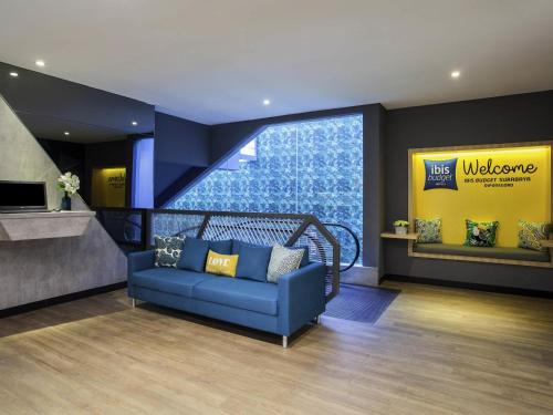 a lobby with a blue couch and a yellow sign at ibis budget Surabaya Diponegoro in Surabaya