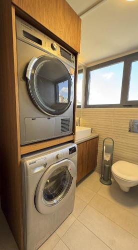 a bathroom with a washing machine and a toilet at NEVO FAQRA Elevate Your Stay! in Ḩaqlat as Sayyid