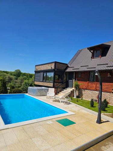 a house with a swimming pool in front of a house at Vikendice Božić in Višnjićevo