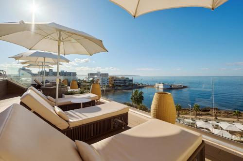 a balcony with chairs and umbrellas and the ocean at AluaSoul Palma Hotel Adults Only in Can Pastilla