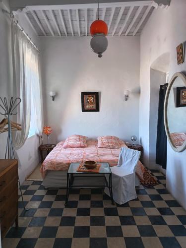 a bedroom with a bed and a table in it at La Maison des Artistes in Essaouira