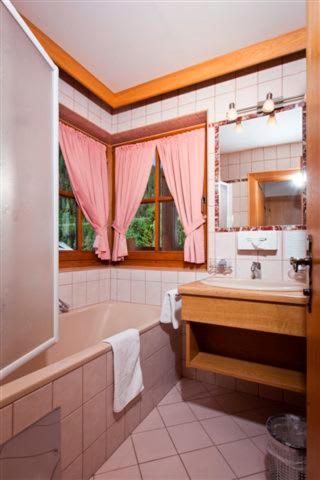 a bathroom with a tub and a sink and a mirror at Hotel Berghof in Nauders