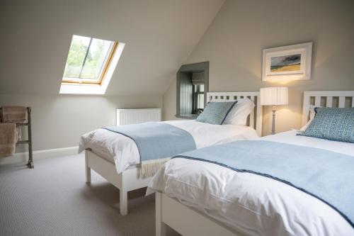 a bedroom with two beds and a window at Riverside Cottage in Comrie