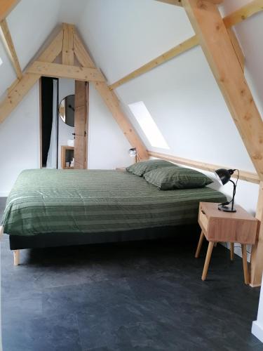 a bedroom with a green bed in a attic at Auberge a la Ferme in Surques