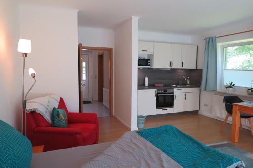 a living room with a red chair and a kitchen at Apartment "An der Süderschmiede" in Sieverstedt