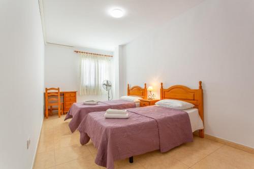 a bedroom with two beds and a table in it at Ático en Candelaria 1 in Candelaria