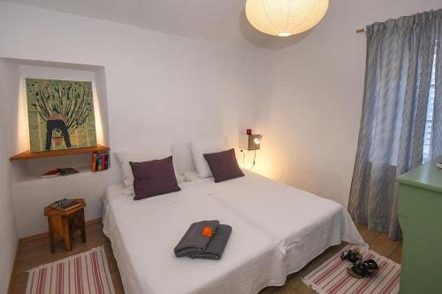 a bedroom with a white bed with a flower on it at Charming Stone House with Green Courtyard in Stari Grad