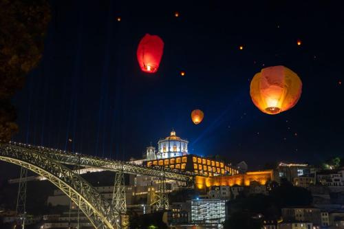 a group of lanterns flying over a bridge at night at Casas São João by Ana Ferro Rentals in Arcozelo